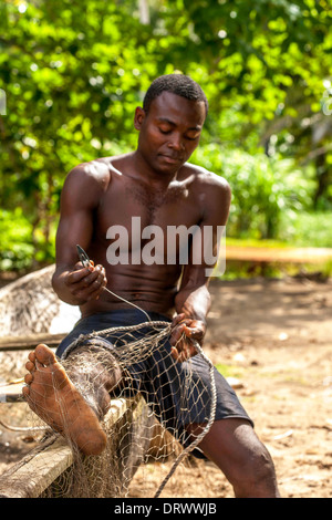 Fisherman repairing fishing net, Principe Island Stock Photo