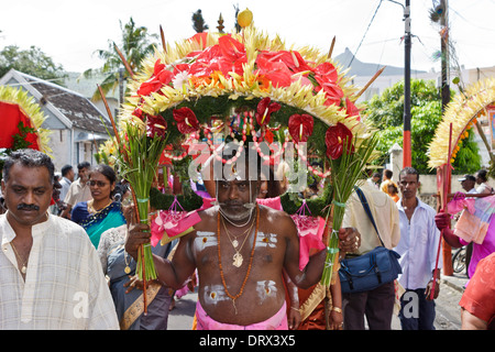 A devotee of Lord Muruga carrying a decorative cavadee and cheeks pierced with a silver spear during the Thaipoosam Cavadee. Stock Photo