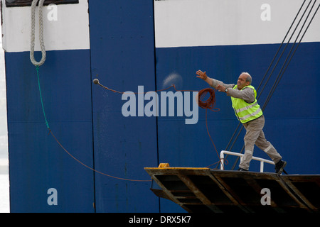 Ship crew guiding heavy duty mooring rope during docking procedure ...
