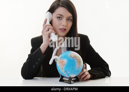 woman using a phone and the cord connected to a globe Stock Photo