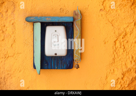 The doorbell button with wooden decoration on the old yellow wall. Stock Photo