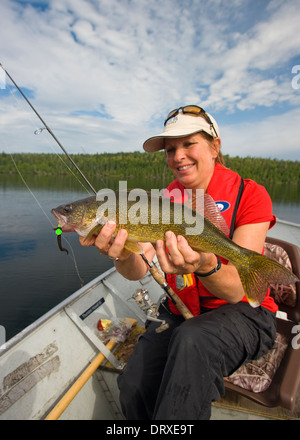 A young girl holds up a winter walleye she caught ice fishing