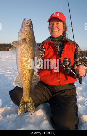 Woman holds up a winter walleye she caught ice fishing. Stock Photo