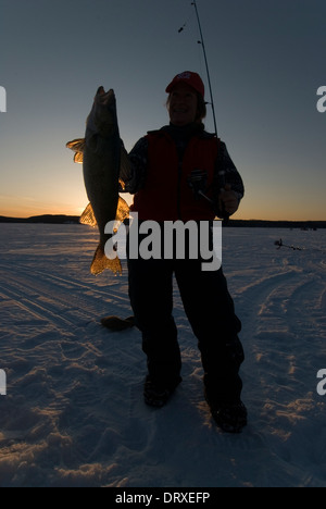 Woman holds up a winter walleye she caught ice fishing. Stock Photo