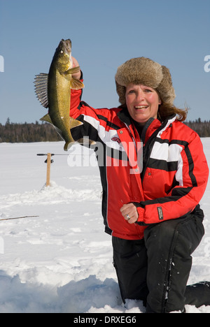 Woman holds up a winter walleye she caught ice fishing. Stock Photo