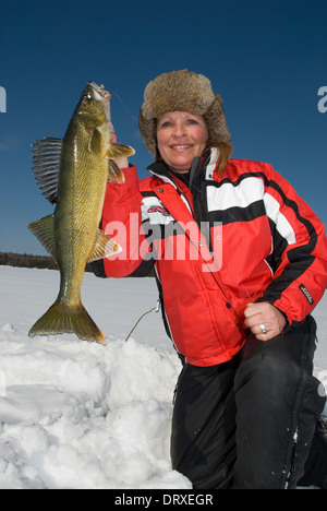 Woman holds up a winter walleye she caught ice fishing. Stock Photo