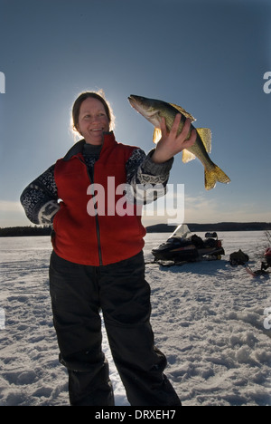 Woman holds up a winter walleye she caught ice fishing. Stock Photo