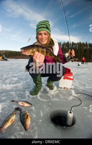 A young woman holds up a winter walleye she caught ice fishing. Stock Photo