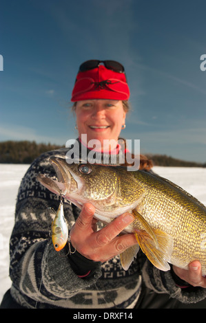 Woman holds up a winter walleye she caught ice fishing. Stock Photo