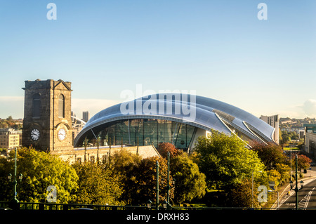 The curved steel roof of the Sage concert venue, with St Mary's Heritage Centre to the left. Gateshead, UK.