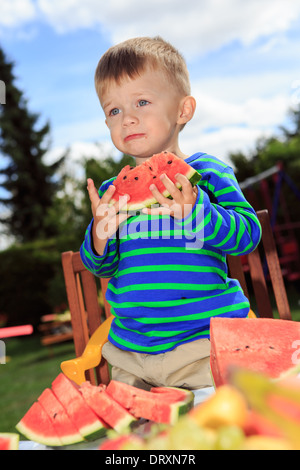 little boy eating a watermelon in the garden Stock Photo