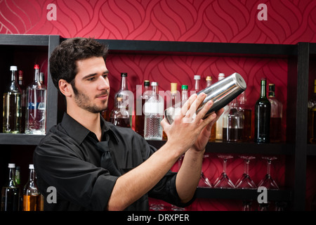 Young bartender make cocktail shaking drinks Stock Photo
