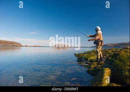 Angler casts off the rocky arctic shore in northern Canada.