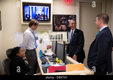 US President Barack Obama talks with Senior Advisor Dan Pfeiffer, right, and Press Assistants Desiree Barnes and Peter Velz in the Lower Press Office prior to delivering a statement regarding budget negotiations in the James S. Brady Press Briefing Room of the White House September 30, 2013 in Washington, DC. Stock Photo