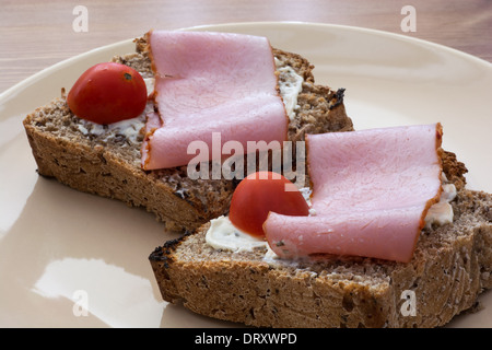 Tasty toasts with butter, ham and cherry tomatoes on the plate. Stock Photo