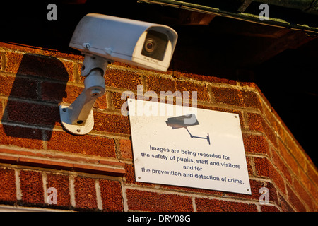 cctv camera and warning notice on a school wall Stock Photo