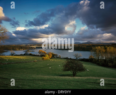 VIEW OVER MENAI STRAIT FROM ANGLESEY LOOKING AT SNOWDONIA MOUNTAINS  WITH MENAI SUSPENSION BRIDGE DESIGNED BY THOMAS TELFORD UK Stock Photo