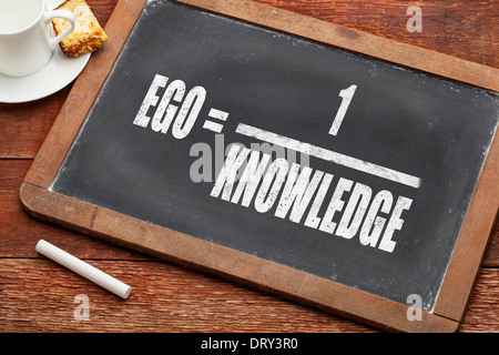 ego and knowledge concept (illustration of Albert Einstein words) on a vintage slate blackboard with a chalk and cup of coffee Stock Photo