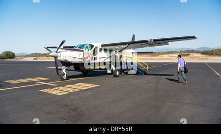 passenger boarding Aerotucan Cessna single engine prop plane sitting on tarmac for flight over mountains from Huatulco to Oaxaca Stock Photo