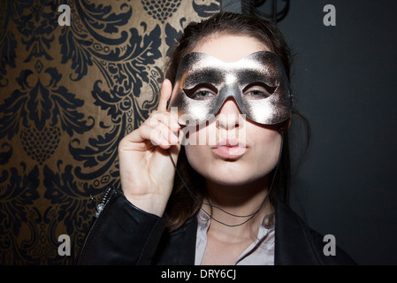 Woman wearing party mask, pursing lips, portrait Stock Photo