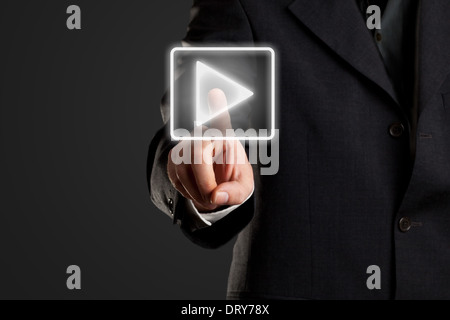Businessman pressing start/ play button on virtual screen Stock Photo