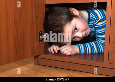 Scared child boy hiding in wardrobe Stock Photo