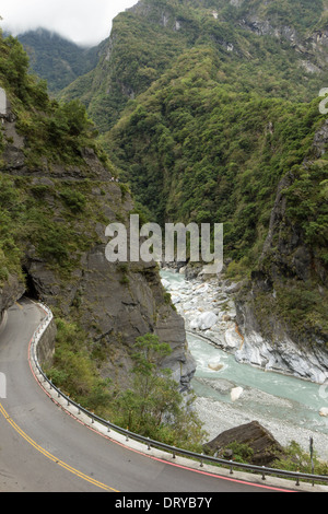 Empty road, river and steep mountains at a rugged and lush landscape at the Taroko National Park in Taiwan Stock Photo