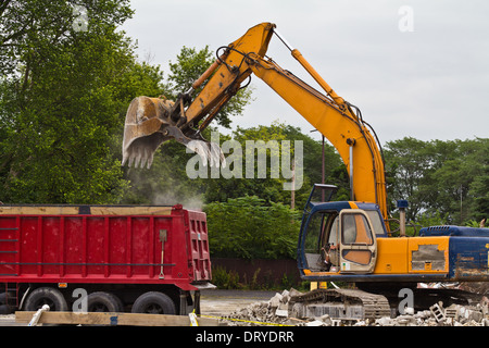 Excavator driver working on construction site digger demolishing building in the city Excavator loads rubble on drump truck in Ohio USA US hi-res Stock Photo