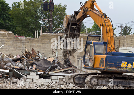 Excavator driver working on construction site digger demolishing building in the city Backhoe Excavator loads rubble in Ohio USA US horizontal hi-res Stock Photo