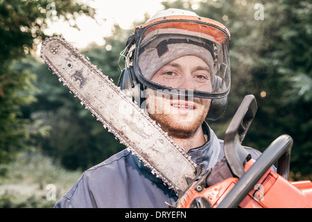 Portrait of professional gardener with chainsaw standing in the garden. Stock Photo