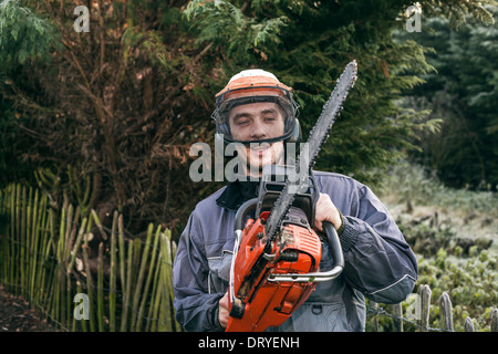 Portrait of professional gardener with chainsaw standing in the garden. Stock Photo