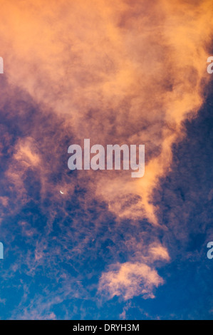 Crescent moon and dramatic pink and orange clouds at sunset, Salida, Colorado, USA Stock Photo