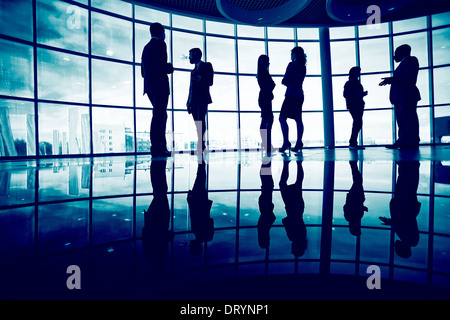 Several white collar workers communicating in office against window Stock Photo