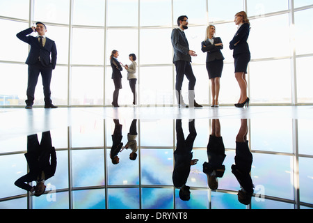 Several white collar workers communicating against window Stock Photo