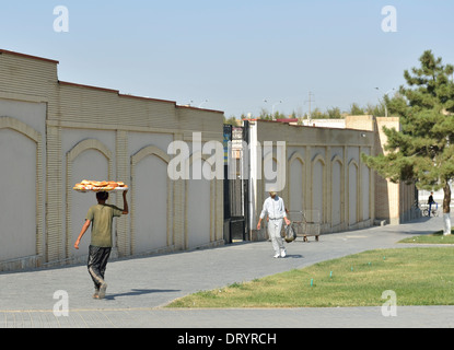 Boy carrying tray of traditional bread to Siyob Bazaar, Samarkand, Uzbekistan Stock Photo