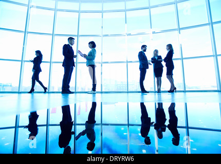 Several white collar workers communicating in office against window Stock Photo