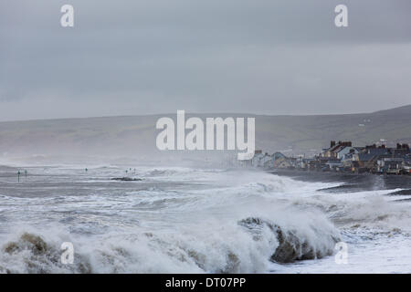 Borth, Ceredigion, Wales, UK. 5th Feb, 2014. The Cardigan Bay coastline continues to be battered as a high tide and moderate wind stir up big waves. The almost unrelenting seas mean constant rebuilding and replacing of tidal defences, such as those built-up during recent years at Borth. Credit:  atgof.co/Alamy Live News Stock Photo