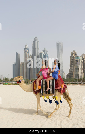Tourists taking a camel ride on beach at Marina district of New Dubai in United Arab Emirates Stock Photo