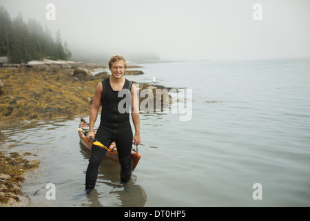 New York state USA man wetsuit kayak onto the shore in misty weather Stock Photo