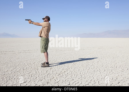 Black Rock Desert Nevada USA man aiming hand gun with his arm outstretched Stock Photo