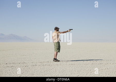 Black Rock Desert Nevada USA Man aiming hand gun standing in vast barren desert Stock Photo