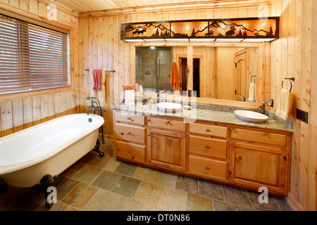 The master bath in a rustic mountain cabin. The room features a claw foot bathtub. Stock Photo