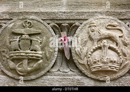 Royal Legion poppy on wooden cross, stone shields of Royal Navy (L) and British Army on side of The Cenotaph war memorial, Bristol, England Stock Photo