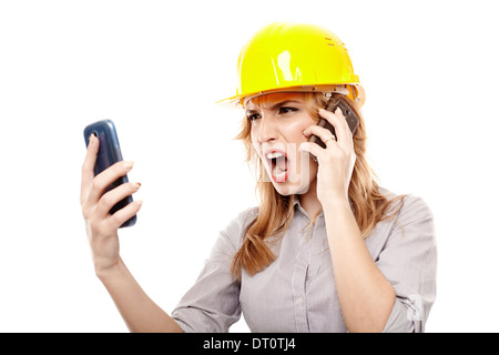 Woman engineer with protection helmet yelling and talking to two cell phones at the same time, isolated on white background Stock Photo