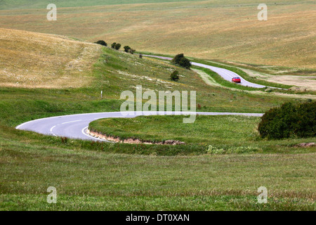 Red car driving along winding road across South Downs near Beachy Head , near Eastbourne, East Sussex , England Stock Photo