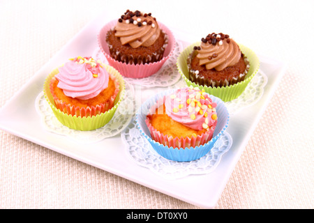 Four appetizing cupcakes on white plate, top view Stock Photo