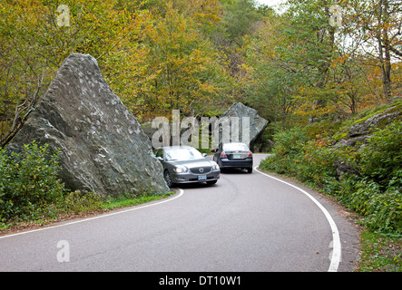 Two cars approach top of Smugglers' Notch (VT 108) through graceful trees on west side of road in Vermont's Green Mountains. Stock Photo