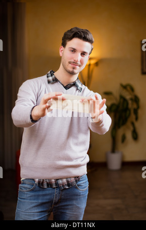 Handsome young man holding check in his hands, smiling and looking at camera Stock Photo
