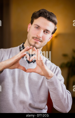 Handsome young man making heart sign with hands, a heart with his fingers Stock Photo