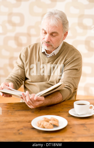 Senior mature man reading book having coffee Stock Photo